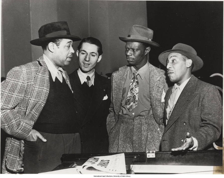 8x10 inch photograph. Duke Ellington, Leonard Feather, Nat "King" Cole, and Johnny Hodges. It is published in Leonard Feather's book The Jazz Years: Earwitness to an era