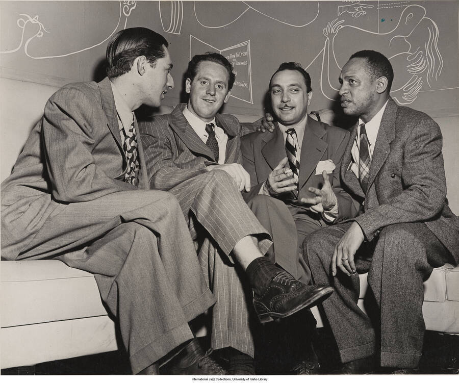 8x10 inch photograph. Handwritten on the back of the photograph: Leonard Feather, Les Paul, French Gypsy guitar wizard Django Reinhardt, and Lionel Hampton at Django's Café Society; uptown opening