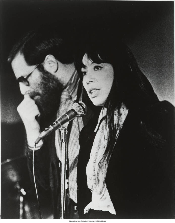10 x 8 inch photograph; Toshiko Akiyoshi and Lew Tabackin. Label on the back of the photograph reads: The internationally acclaimed Akiyoshi/ Tabackin Big Band, winner of the Downbeat Readers and Downbeat Critics Polls for 1981 as the Number One Big Band, will appear in a rare concert at UCLA's Royce Hall, Saturday, January 30 at 8:30 p.m.