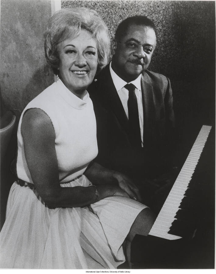 10 x 8 inch photograph; a woman and a man at the piano. Handwritten on the back of the photograph: Teddy Wilson and M.; taken at the Plaza Hotel, Rochester, NY, 1969