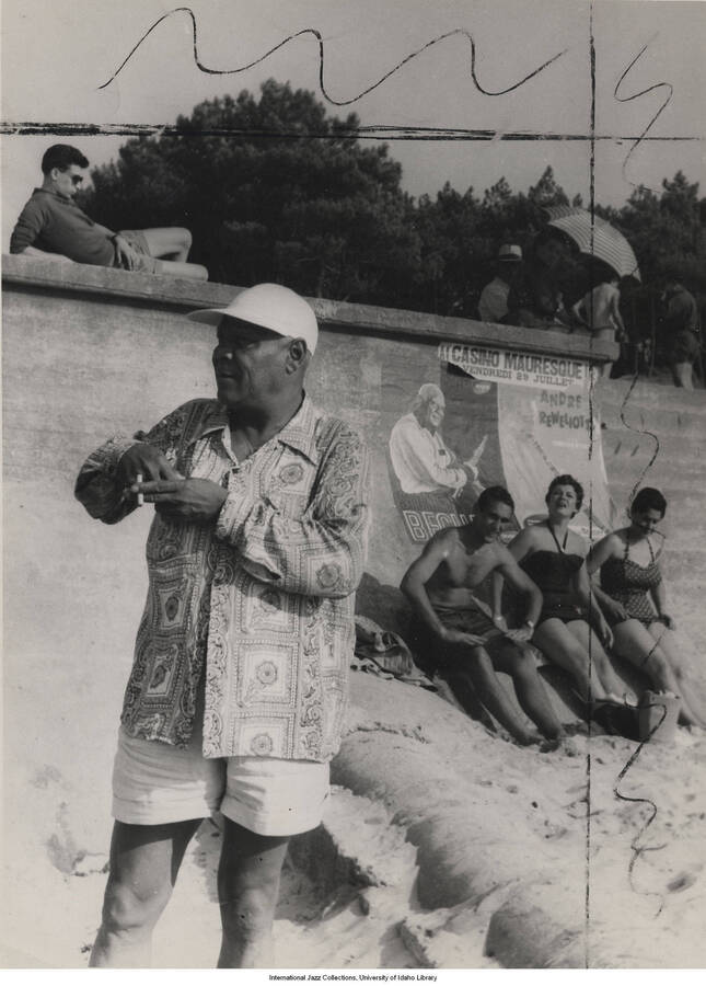9 1/2 x 7 inch photograph; Sidney Bechet at the beach. Observable in the background is a poster, written in French, that reads: Casino Mauresque; Sidney Bechet