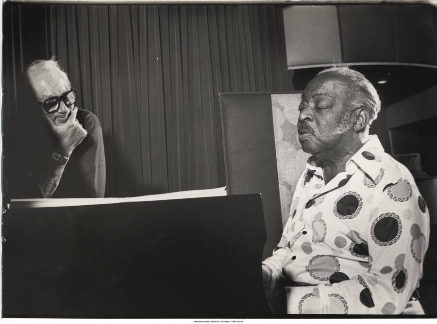 11 x 14 inch photograph; Count Basie playing the piano and Norman Granz leaning on it