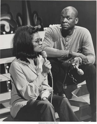 10 x 8 inch photograph; Brock Peters with an unidentified woman holding microphones