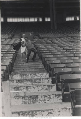 5 x 3 1/2 inch photograph; unidentified press photographer and man, climbing down the steps of a stadium