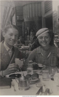5 3/8 x 3 3/8 inch photograph in post card format; Leonard Feather and a woman in an outdoor café. Handwritten on the back of the photograph: Beatrice Mills