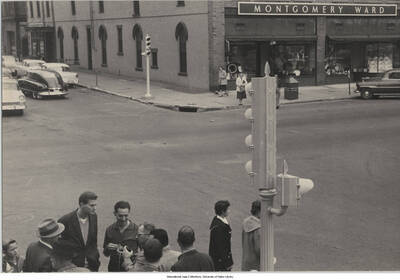 6 1/2 x 9 1/2 inch photograph; Leonard Feather and unidentified persons on a street. Observable in the background is the Montgomery Ward department store