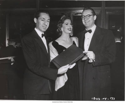 8x10 inch photograph. Leonard Feather with Jayne Meadows and Steve Allen. Leonard Feather is presenting a  portfolio to Steve Allen, that reads on the cover: To Steve Allen