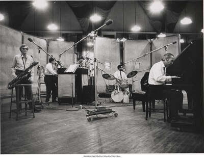 7 x 9 inch photograph; Dave Brubeck performing with baritone saxophonist Gerry Mulligan, drummer Alan Dawson and several unidentified musicians.