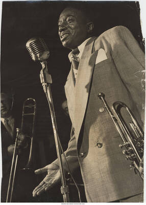 13 1/2 x 9 3/4 inch photograph; Hot Lips Page at the microphone holding the trumpet on his left side