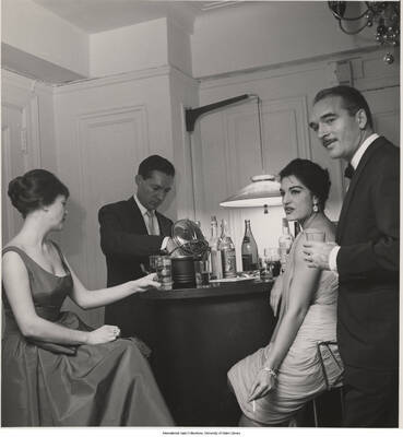 14 x 11 inch photograph; Jane and Leonard Feather with unidentified persons in a reception, probably in their apartment