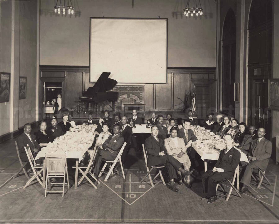 Unidentified persons sitting at a dinner table in what appears to be the gym or auditorium of a school. [Young Men's Christian Association, Pottstown, Pennsylvania]