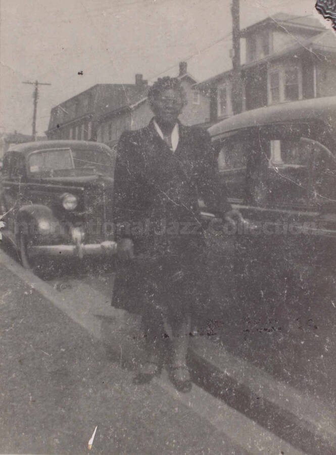 Unidentified woman posing beside a car