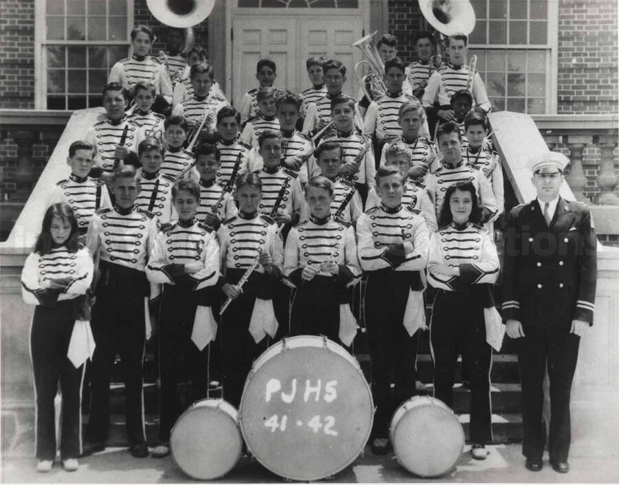 A band posing on the steps of a brick building. Written on the drum: PJHS 41.42