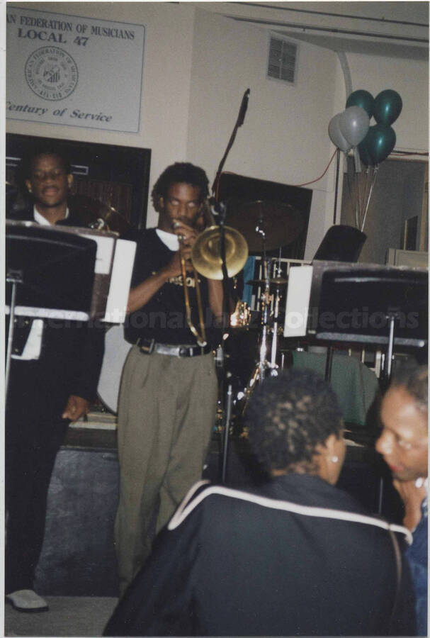 Unidentified musicians. A sign on the wall behind the stage reads: American Federation of Musicians, Local 47