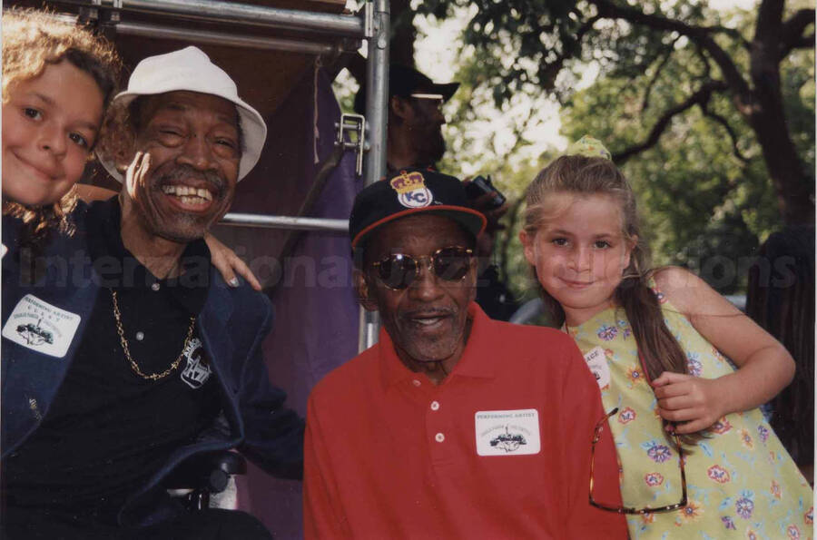 Al Grey posing with two unidentified girls and an unidentified musician at the Sixth Annual Charlie Parker Jazz Festival