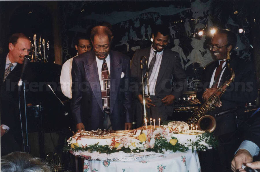 Al Grey celebrating his 70th birthday with unidentified musicians at the Tavern on the Green, in New York (NY). An invitation to the party accompanies the photograph