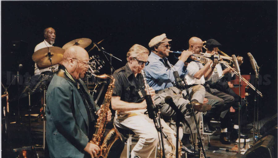 Al Grey performing with unidentified musicians [in Tokyo?]. Projected on the wall behind the stage are the words: Statesmen of Jazz