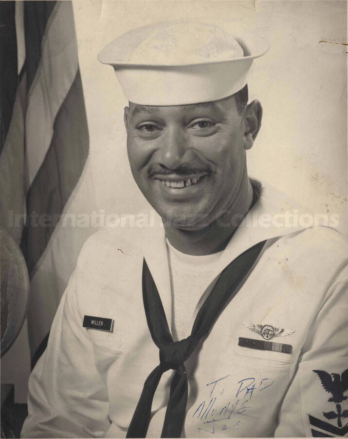 Portrait of a man in military costume. A badge name on the right side of his shirt reads: Miller. This photograph is dedicated to dad by [?] Joe