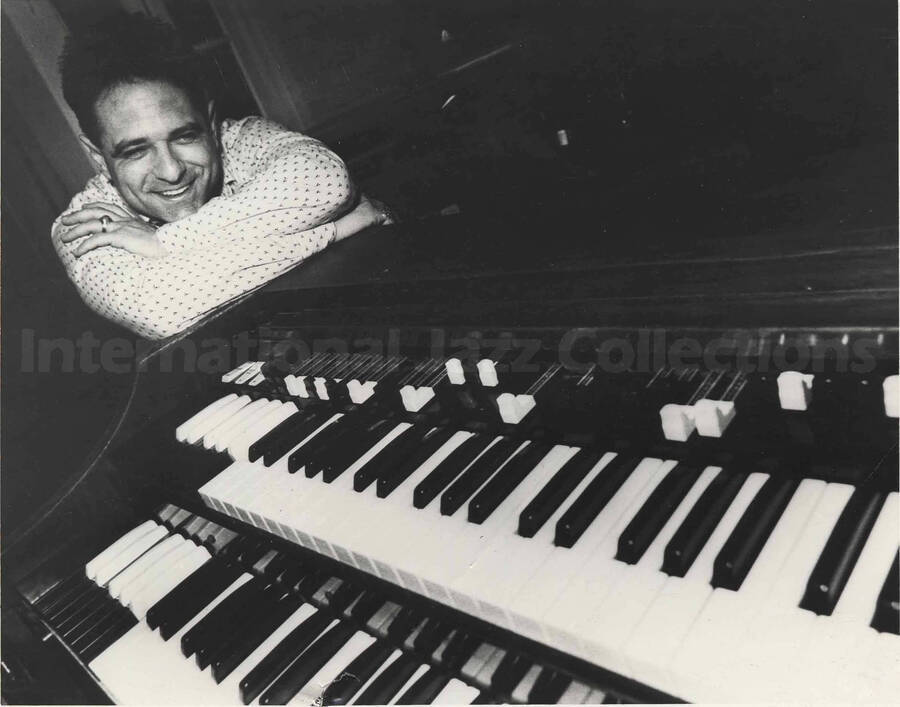 Unidentified man leaning on a piano