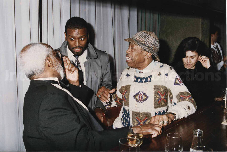 Al Grey with two unidentified men and an unidentified woman at the counter of a tavern. A label on the back of the photograph reads: Sunday 1992-11-01.  Jazz Mecca 1992/Maastricht-The Netherlands; Golden Tulip/Barbizon Hotel-Maastricht