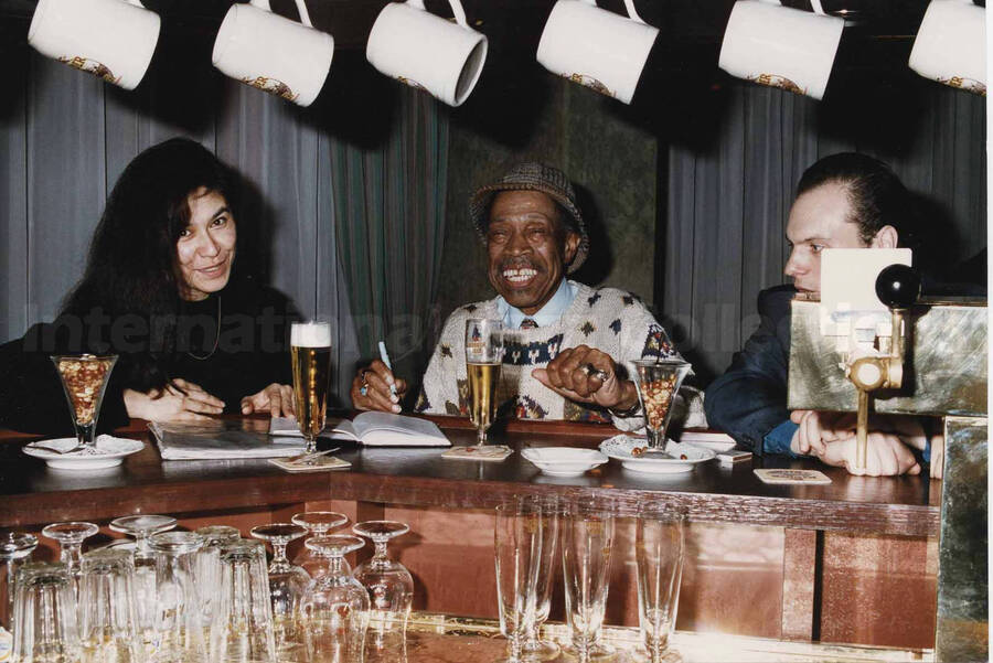 Al Grey with unidentified men and woman at the counter of a bar. A label on the back of the photograph reads: Sunday 1992-11-01. Jazz Mecca 1992/Maastricht-The Netherlands; Golden Tulip/Barbizon Hotel-Maastricht
