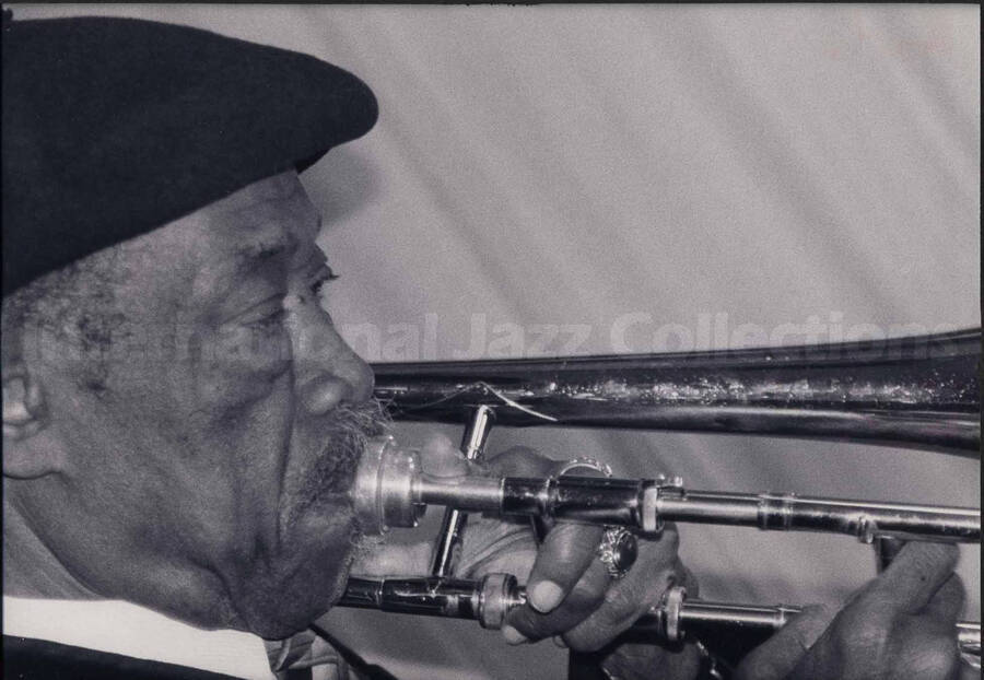 Al Grey playing the trombone. The photograph is mounted on a black mat. Handwritten on the mat bellow the photograph: Bill Kreisberg. "So Smooth";  1996
