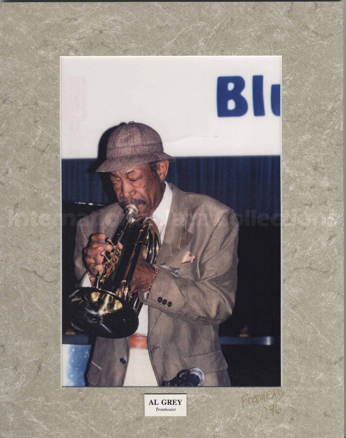 Al Grey playing the trumpet at the Blue Note, New York. The photograph is mounted on a grey mat. Accompanying the photograph is the photographer visit card