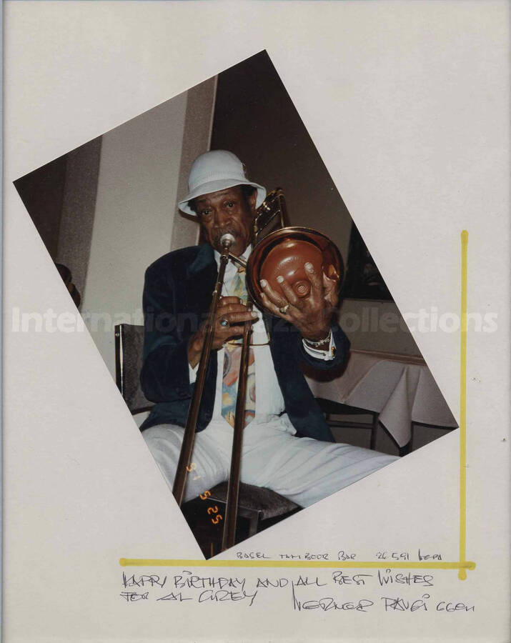 Al Grey playing the trumpet. The photograph is pasted on a white mat, which bears a signed dedication to Al Grey for his birthday. The photograph is in a 17 x 11 1/2 wood frame