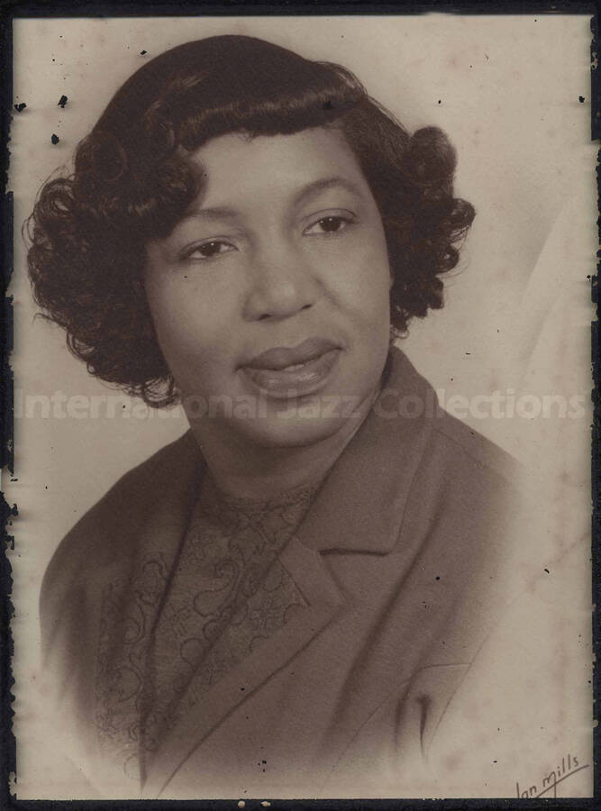 Portrait of an unidentified woman. The photograph is under glass in a metal desk frame. The easel of the frame is separated. No inscriptions on the back of the photograph