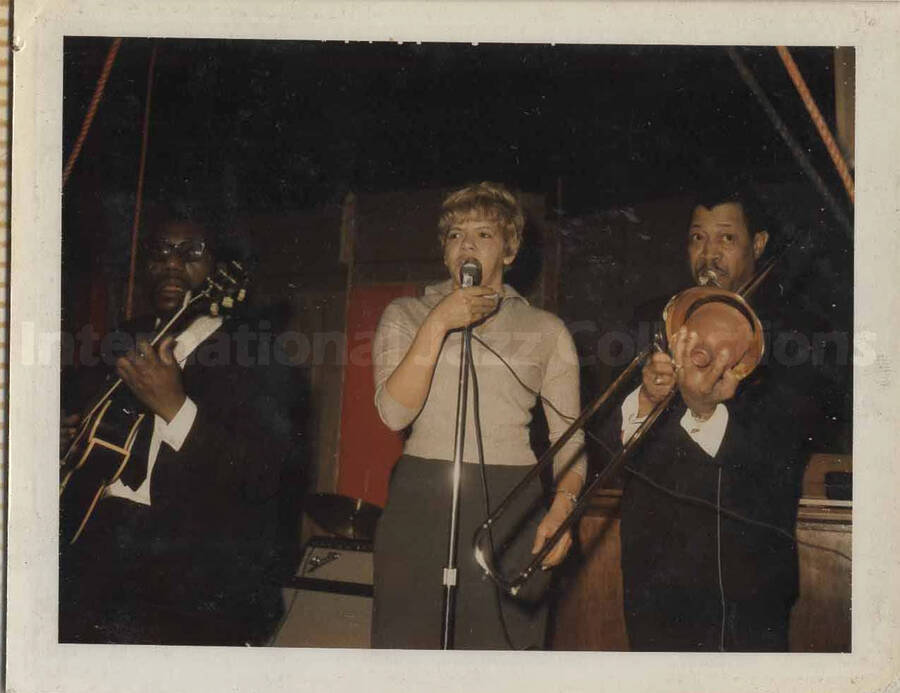 Al Grey performing with two unidentified musicians. This photograph is pasted on a photo album sheet.
