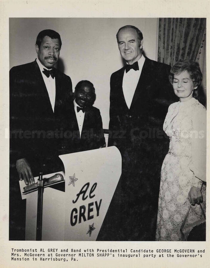 Inscription at the bottom of the photograph reads: Trombonist Al Grey and Band with Presidential Candidate George McGovern and Mrs. McGovern at Governor Milton Shapp's inaugural party at the Governor's Mansion in Harrisburg, PA. This photograph is pasted on a photo album
