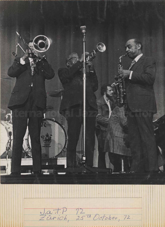 Al Grey performing with trumpeter [Roy Eldridge] and saxophonist [Coleman Hawkins] at the Jazz at the Philharmonic- JATP, in Zurich. The name on the drums read: Louie Bellson. This photograph is pasted on a photo album
