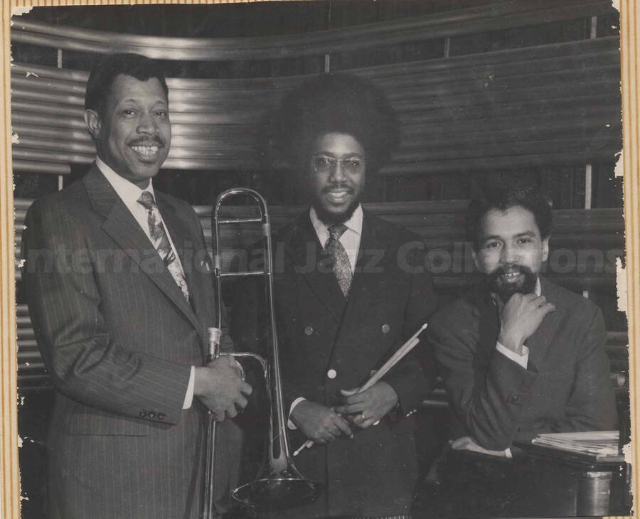 Al Grey posing with two unidentified musicians. This photograph is pasted on a photo album sheet.