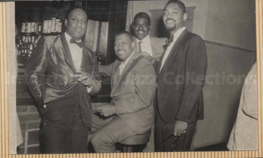 Al Grey posing with three unidentified men . This photograph is pasted on a photo album sheet.