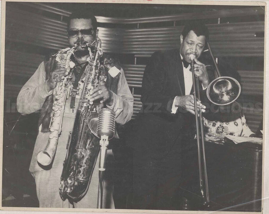 Al Grey performing with Rahsaan Roland Kirk, who is playing both a saxophone and another woodwind instrument. This photograph is pasted on a photo album