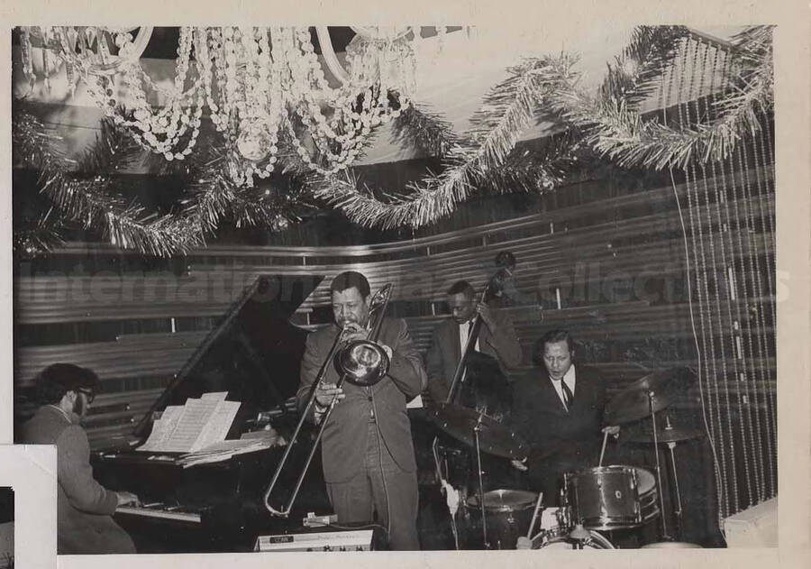 Al Grey performing with unidentified musicians . This photograph is pasted on a photo album sheet.
