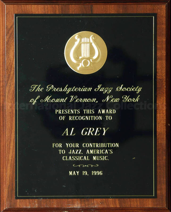 Wood finish plaque with black engraved plate bearing a disk. To Al Grey from the Presbyterian Jazz Society of Mount Vernon, New York. A label on the back of the plaque reads: Trophy Madness; R & F Trophies, New Rochelle (NY)