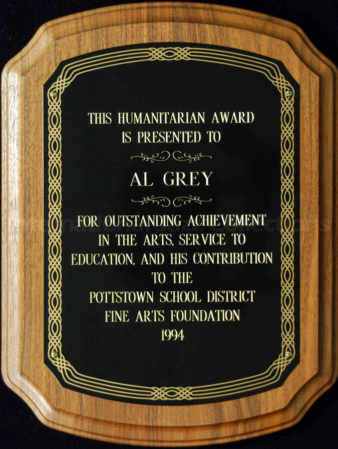 Scallop walnut finish plaque with black engraved plate. Humanitarian Award presented to Al Grey by the Pottstown School District Fine Arts Foundation for his service to education and contribution to the foundation. Stamped on the back of the plaque: Trophy & Plaque Shack, Pottstown (PA)