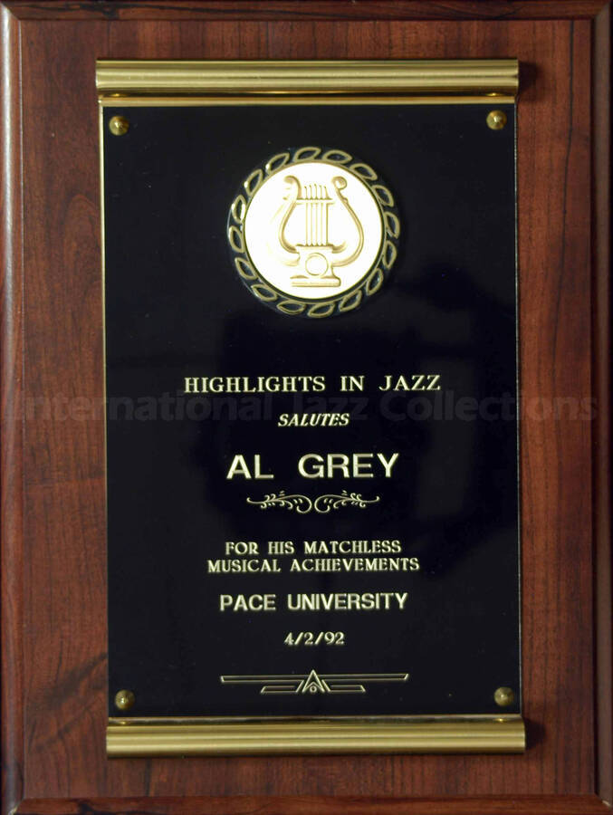 Wood finish plaque with double engraved plate bearing a disk. To Al Grey from Pace University. A label on the back of the plaque reads: Trophy World, Brooklyn (N.Y.)