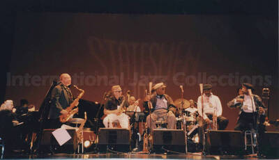 Al Grey performing with unidentified musicians [in Tokyo?]. Projected on the wall behind the stage are the words: Statesmen of Jazz