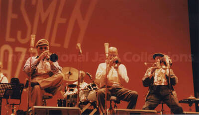 Al Grey performing with unidentified musicians [in Tokyo?]. Projected on the wall behind the stage are the words: Statesmen of Jazz