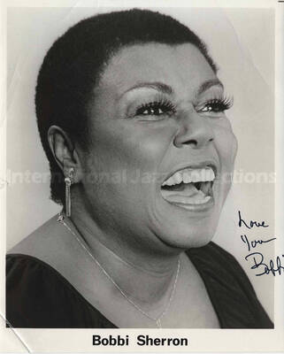 Bobbi Sherron. On the back of the photograph there is a ticket from D.R. Jellis and associates, Canada, and a handwritten note: Please bring horn to Philly. Photograph is signed.