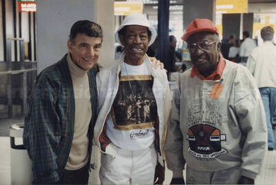 Al Grey (center) posing with drummer Louie Bellson (left) and an unidentified man (right). A label on the back of the photograph reads: Sunday 14th, 1991. 16th North Sea Jazz Festival 1991/The Hague; Amsterdam Airport (Departure)