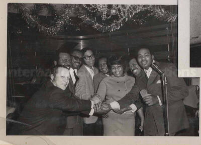 Al Grey posing with unidentified persons. This photograph is pasted on a photo album sheet.