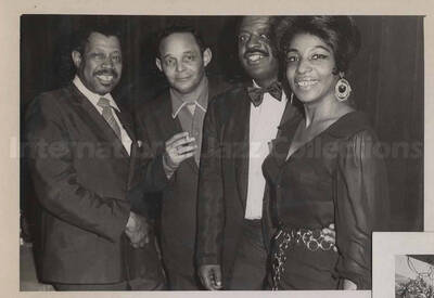 Al Grey posing with two unidentified men and an unidentified woman. This photograph is pasted on a photo album sheet.