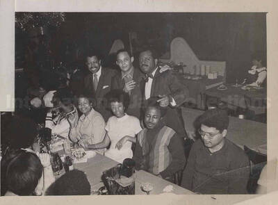 Al Grey posing with unidentified persons. This photograph is pasted on a photo album sheet.