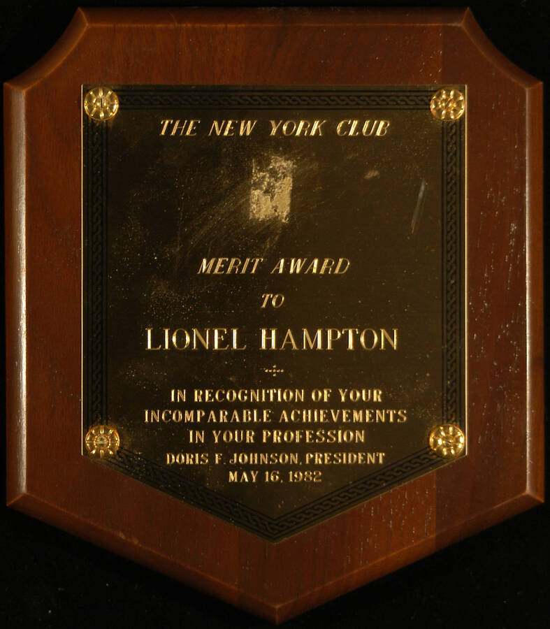 Plaque. 8"x7" Shield wood finish plaque with engraved plate The New York Club Merit Award to Lionel Hampton in recognition of his achievements in his profession. Doris F. Johnson, President. May 16, 1982