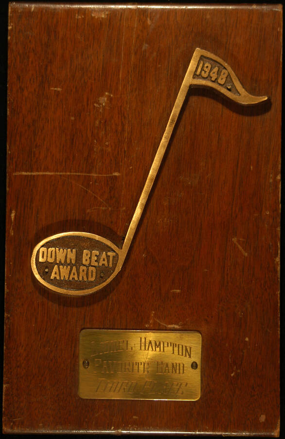 Plaque. 10"x6 3/8" Wood finish plaque with musical theme and engraved plate Down Beat Award presented to Lionel Hampton Favorite Band Third Place. 1948