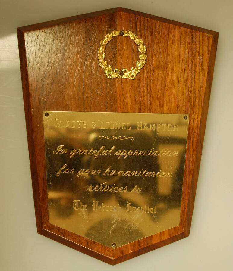Plaque. 10"x8" Shield wood finish plaque with wreath and engraved plate To Gladys and Lionel Hampton in grateful appreciation for their services to the Deborah Hospital
