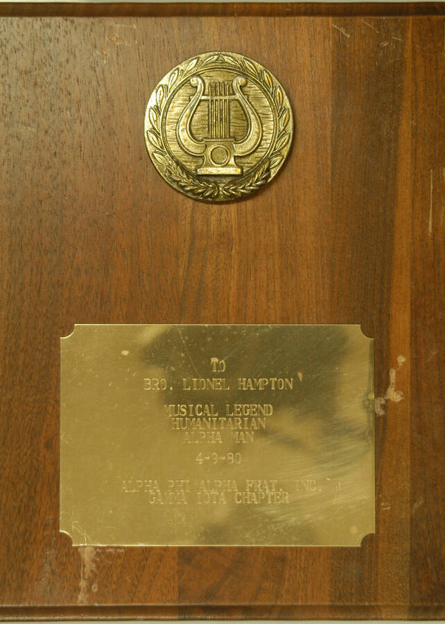 Plaque. 10"x8" Wood finish plaque with disc and engraved plate Musical Legend Humanitarian Alpha Man presented to Lionel Hampton by the Alpha Phi Alpha Frat., Gamma Iota Chapter. Apr. 9, 1980